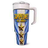 A travel tumbler with a white handle and lid, featuring a blue and white vertical striped design with the text 'CAMPEONES DEL MUNDO' in yellow and three gold stars.